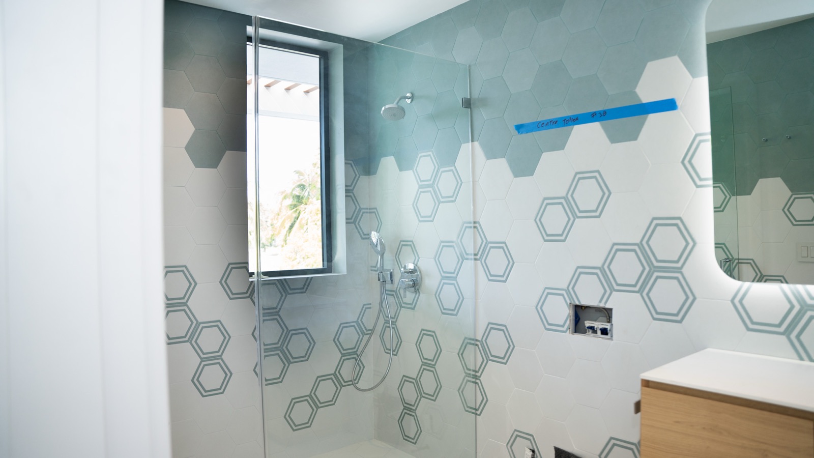 Walk-in shower with hexagon tile and glass panel