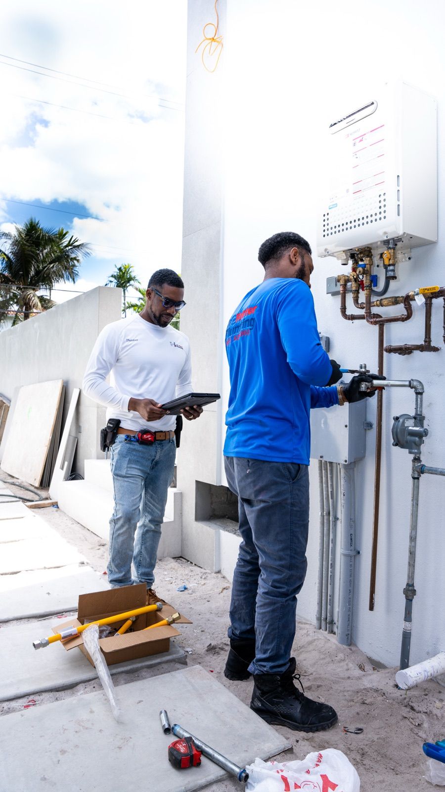Two Dr. Rooter Plumbing technicians reviewing a tankless water heater installation
